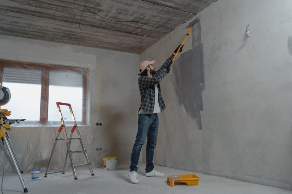Decorator painting a wall with a roller on an extension pole